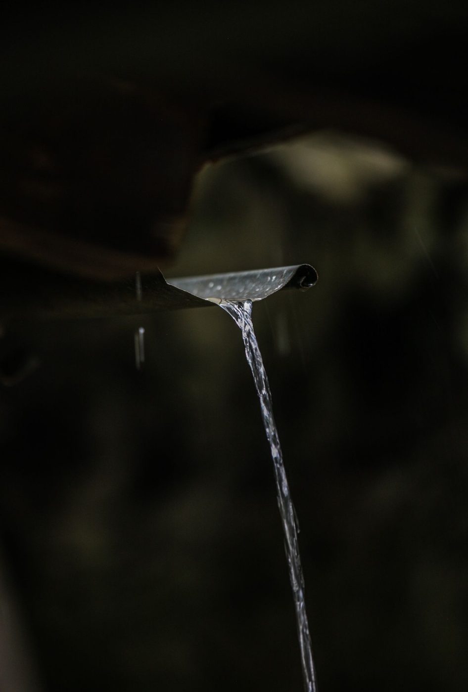 Water flowing freely from a clean, well-functioning gutter downspout